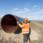 Pipeline workers measuring tube length for construction of gas and oil pipes.